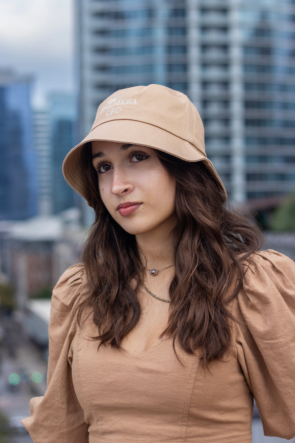 Woman wearing a beige bucket hat and top in an urban setting