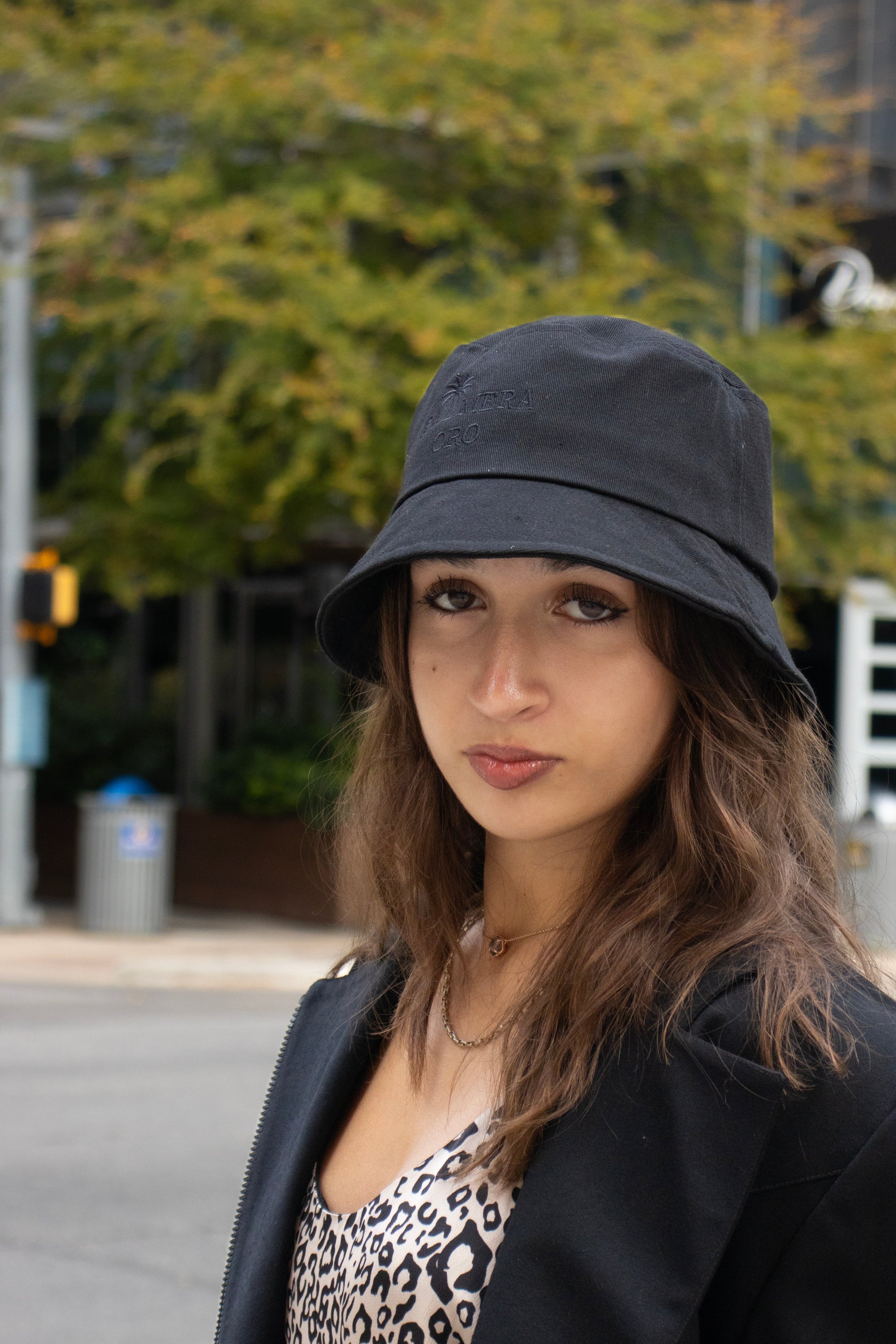 Woman wearing a black bucket hat and black jacket on a city street.