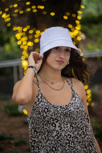 Woman wearing a white bucket hat and leopard print top with blurred lights in the background