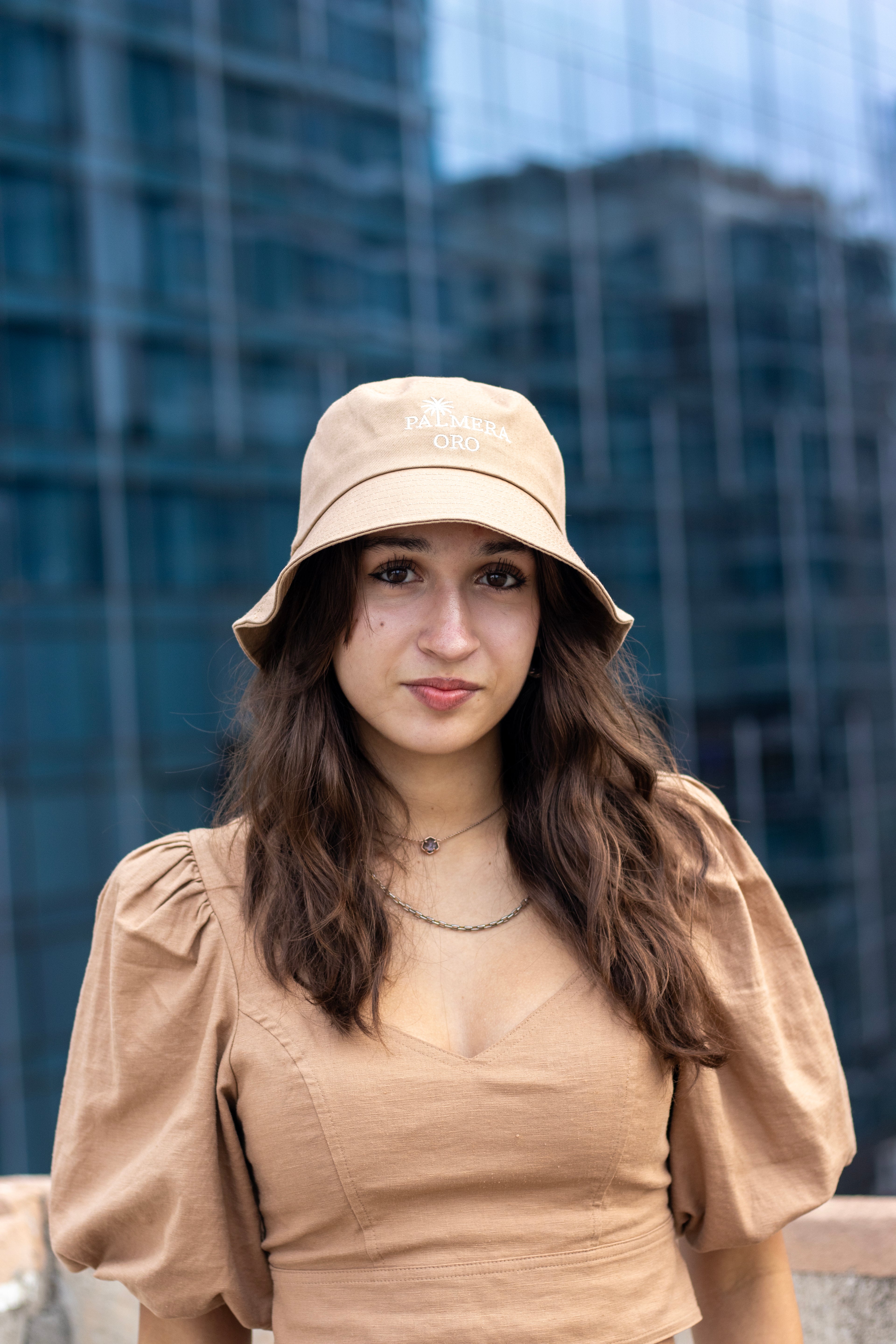 Woman wearing a beige bucket hat and top in an urban setting
